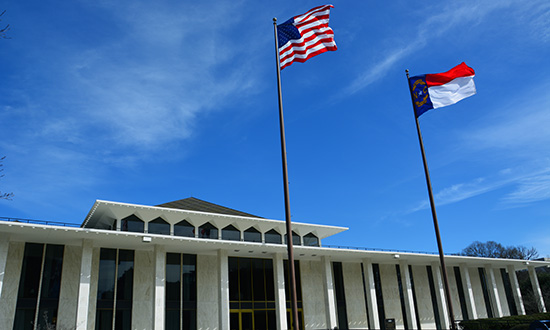 The exterior of the North Carolina Legislative building with U.S. and North Carolina flags.
