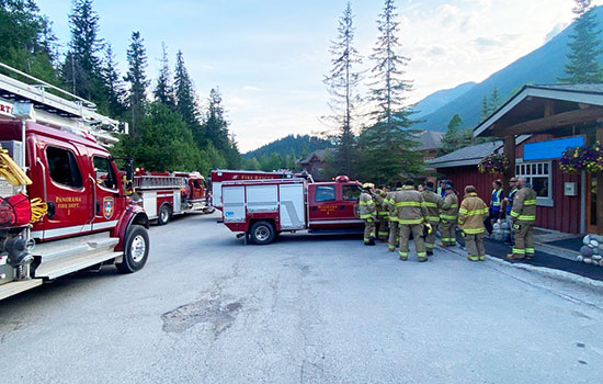 Fire and utilities personnel congregate outside for emergency training with fire vehicles.